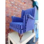 A purple striped armchair, raised on cabriole legs. The upholstery in this lot does not comply with