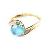 A 9ct gold blue topaz and cz set twist ring, the central blue topaz in four claw setting, with white