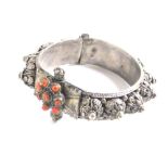 A highly elaborate Middle Eastern bangle, the clasp set with orange stones, the body with raised flo