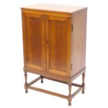 A 1920's oak coin cabinet, the top with a moulded edge, above two panelled doors with removable shel