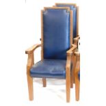 A pair of oak library type armchairs, each with a blue leatherette padded high back and seat, shaped