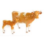 A Beswick Guernsey cow, 12cm high, and calf, printed marks beneath. (2, AF)