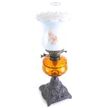 An early 20thC oil lamp, with clear chimney, frosted glass shade, amber glass reservoir and iron sta