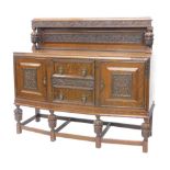 A 1920/30's oak sideboard, the raised back carved with grapes and vines, and with cup and cover supp