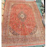A large red ground Persian Mashad carpet, with central navy medallion, on a red floral ground with n