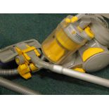 A Dyson vacuum cleaner, in yellow and grey trim, with accessories.