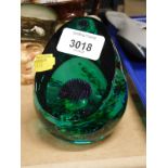 A Caithness style glass paperweight, in green set with thistle, 13cm high.