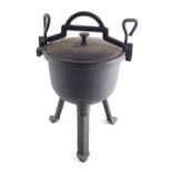 A wrought iron Dutch cooking pot, with screw top on shaped legs, 35cm high.