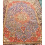 A vintage Persian Tabriz carpet, with central flower shaped medallion in red, on a blue ground with