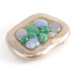 A polished pewter and applied pebble compact, shaped with green and clear stones, 8cm x 5cm.