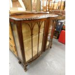 A walnut double bow fronted glazed display cabinet, on cabriole legs with ball and claw feet.