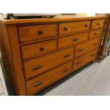 A pine effect side board or dresser with an arrangement of ten drawers on bun feet.