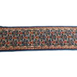 A Caucasian blue ground runner, embroidered with three rows of repeating geometric motif within flor