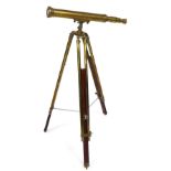 A brass telescope, on a brass and wooden tripod stand, 63cm wide.