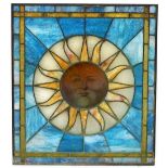 A stained glass window, decorated with the full sun, against a blue ground, 84cm high, 74cm wide.