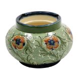 A Moorcroft Macintyre and Co Florian ware pottery tobacco jar, decorated with flowers against a text