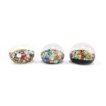 Three millefiori glass paperweights, two with mixed tight canes, each 6cm wide.