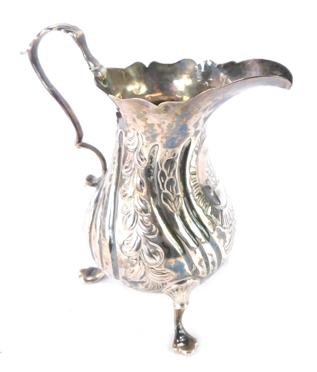 A George III silver cream jug, with embossed rococo floral and foliate decoration, vacant shield