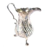 A George III silver cream jug, with embossed rococo floral and foliate decoration, vacant shield