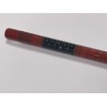 An Indian early 20thC red and black lacquer walking cane, with bands of geometric decoration, 93cm