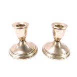 A pair of silver dwarf candlesticks, each with a ribbed top on a weighted base, stamped Sterling,