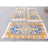 An Eastern wool rug, rectangular with blue border and central flower design, white tassel ends. (3)