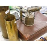 A two brass artillery shells, a brass burner and a suitcase.