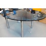An oval glass top dining table, on metal base, 72cm high, the top 123cm x 177cm. Note: VAT is payabl