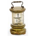 An early 20thC flip ticket clock, in a cylindrical brass coated tin case with Perspex front, and car