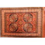 A Persian wool and silk mix red ground rug converted to a wall hanging, decorated with four central