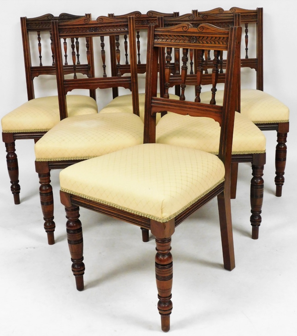 A set of six Edwardian walnut dining chairs, upholstered in overstuffed gold fabric, raised on turne