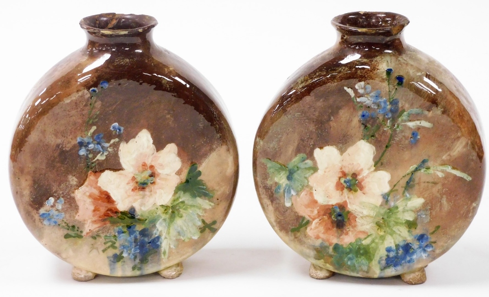 A pair of late 19thC Minton pottery moon flasks, painted with flowers against a brown ground, one be