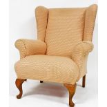 A Georgian style oak framed wingback armchair, upholstered in diamond pattern fabric, raised on cabr