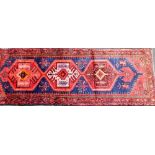 A Persian Hamadan runner, on a red and blue ground, 278cm x 103cm.
