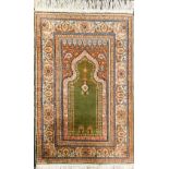 A Persian cream ground prayer rug, the green Mihrab, with hanging lantern and flowers, within foliat