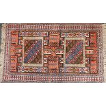 A Persian Kurdish red ground rug, with four central rectangular fields, containing geometric motifs