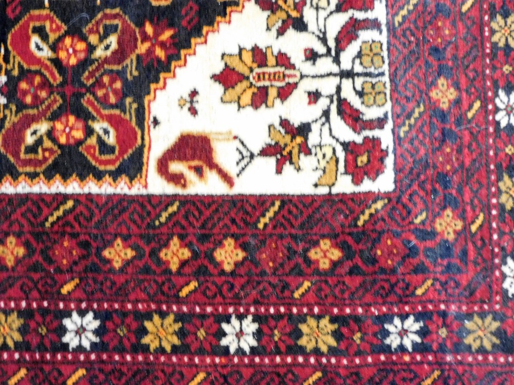 A Persian rug, possibly Quchan, with a central floral and foliate ground, within a red border of rep - Image 2 of 3