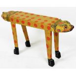 A Balinese painted wooden cat stool, with double headed ends, the body painted with red spots, raise