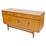A mid century G-Plan teak sideboard, one long fitted and two short drawers, over four cupboard doors