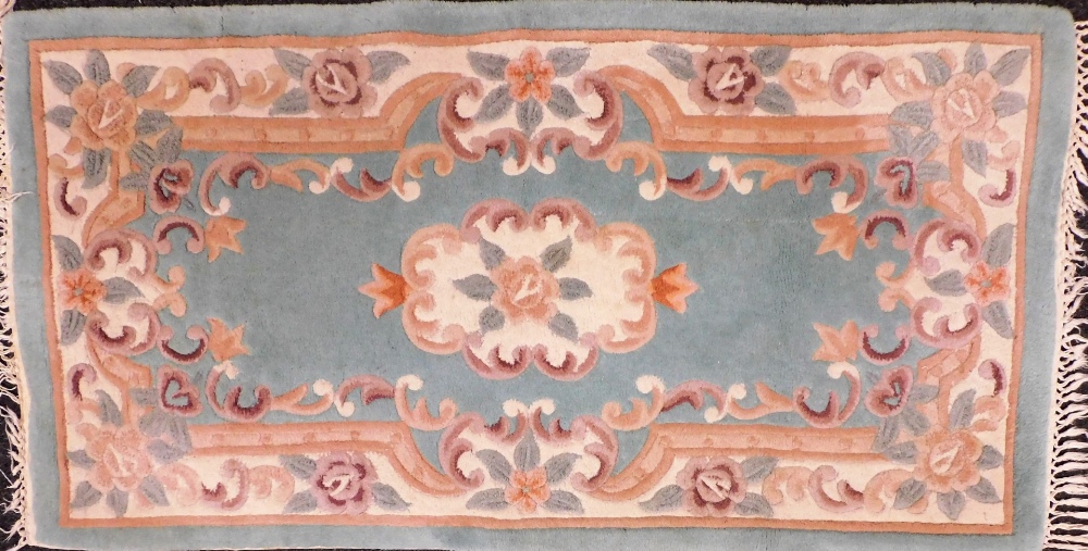 A Chinese turquoise blue ground rug, with floral decoration, 150cm x 78cm.