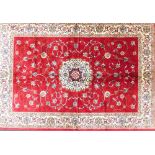 A Cashmere rug, on a rich red ground with full pile and medallion design, 170cm x 120cm.