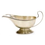 A George V silver sauce boat, with a gadrooned border on pedestal base, Birmingham 1927, 5oz, 7cm hi