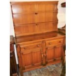 An Ercol elm dresser, with a two shelf waterfall plate rack, over a pair of doors above cupboard doo