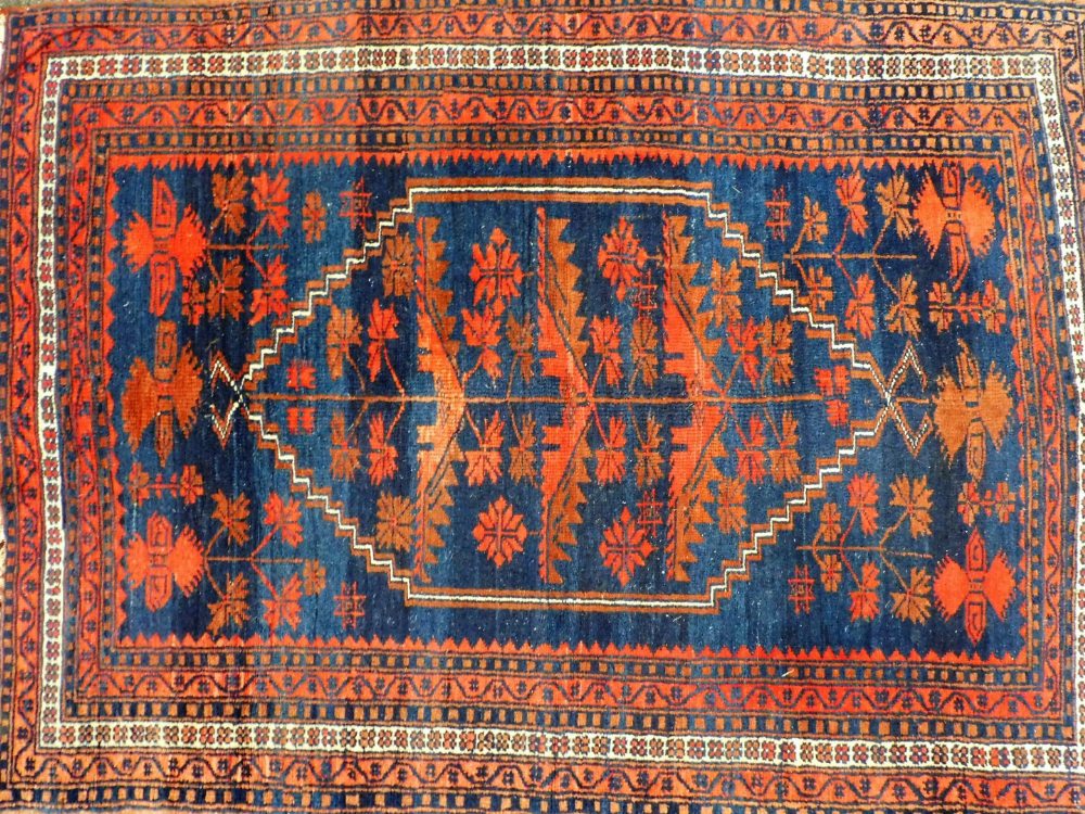 A Caucasian red ground rug, decorated with a central medallion containing floral motifs, within flor