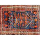 A Caucasian red ground rug, decorated with a central medallion containing floral motifs, within flor