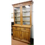 A Victorian oak cupboard bookcase, the out swept pediment over a pair of glazed doors enclosing thre