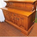 A Continental Gothic oak style sideboard, with a panelled back over a carved frieze drawer above a p