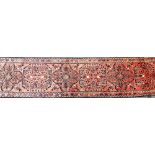 A Persian runner, on a washed red ground with floral medallion design, 365cm x 80cm.