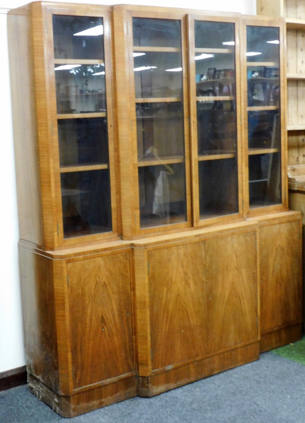 An Art Deco walnut breakfront bookcase, the top with four glazed doors, each enclosing three shelves