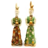 A pair of Chinese Tang style terracotta tomb figures, with brown, cream and green glazes, each holdi